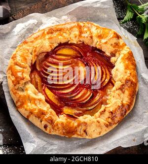 Pfirsich-Gallete auf Backpapier auf Holzhintergrund. Frisch zubereiteter hausgemachter Kuchen. Draufsicht, flach liegend Stockfoto