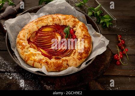 Pfirsich-Gallete auf Backpapier auf Holzhintergrund. Frisch zubereiteter hausgemachter Kuchen. Stockfoto