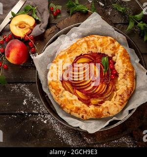 Pfirsich-Gallete auf Backpapier auf Holzhintergrund. Frisch zubereiteter hausgemachter Kuchen. Draufsicht, flach liegend Stockfoto