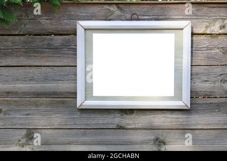 Selbstgemachte Malerei in einem weißen Holzrahmen, der an einem rustikalen Zaun hängt Stockfoto
