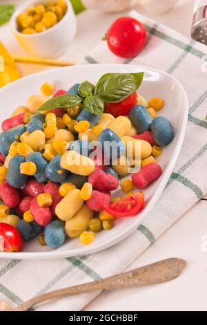Farbige Gnocchi mit Gemüse und süßem Mais. Stockfoto