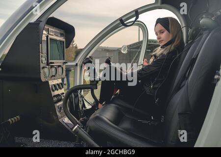 Nachdenkliche Tween Mädchen in schwarz sitzt auf Copilot Sitz im Hubschrauber Stockfoto