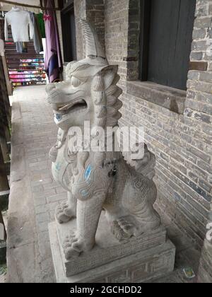 Eine steinerne Löwenhund-Schutzstatue mit einem Horn in einem Haus in der Nähe des Hui Guang Tempels im alten Bezirk Lizhuang Stockfoto