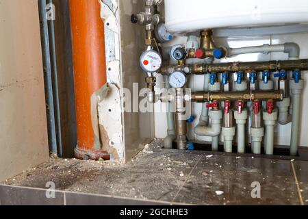 Komplexes Wasserverteilungssystem im Waschraum bei Reparaturen zum Austausch der Steigleitung und der Rohre. Komplexes Rohrleitungssystem mit heißen und kalten Wasserleitungen w Stockfoto