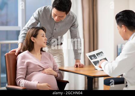 Arzt im Gespräch mit einer Schwangeren im Büro Stockfoto