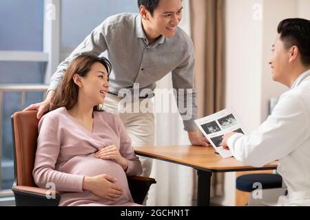Arzt im Gespräch mit einer Schwangeren im Büro Stockfoto