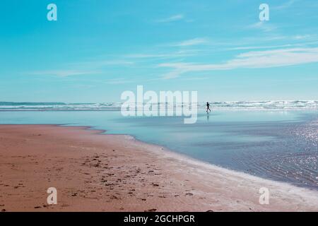 Silhouette eines einjährigen Joggers am Strand von Mawgan Porth, Cornwall, Großbritannien Stockfoto