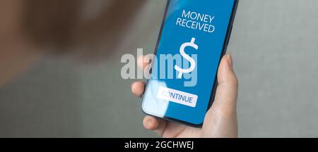 E-Banking und E-Commerce-Konzept. Frau, die ein Mobiltelefon mit Online-Banking-Anwendung verwendet, erhält Geld im Hintergrund Stockfoto