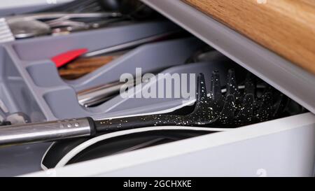 Person schließt ausziehbare Küchenschublade mit Utensilien Stockfoto