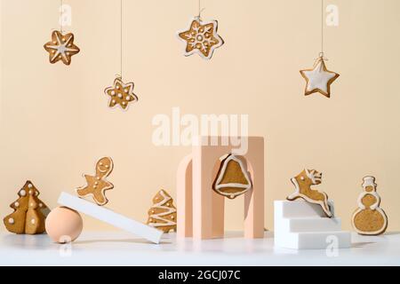 Weihnachtliche Komposition mit Lebkuchenkeksen im trendigen minimalistischen Stil. Verschiedene geometrische Formen, Podien und weihnachtskekse auf neutralem cremefarbenem Hintergrund Stockfoto