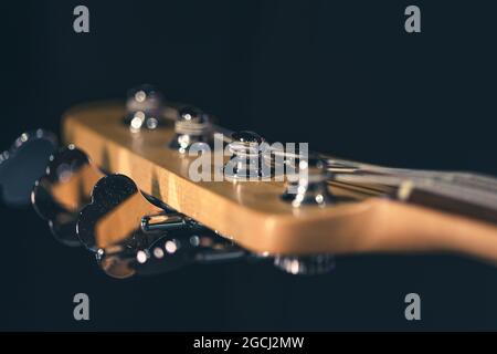 Detail eines Stimmpfostens auf dem hölzernen Kopfstock einer E-Bass-Gitarre. Stockfoto