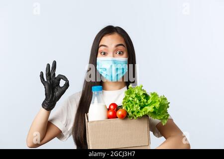 Covid-19, Lebensmittelgeschäft, Beschäftigung, Kleinunternehmen und Virus-Konzept. Enthusiastisch niedlich asiatische Shop Arbeiter Verpackung Ihrer Online-Bestellung, hält schlecht mit Stockfoto