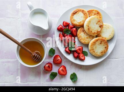 Quark-Pfannkuchen, Ricotta-Fritten auf Keramikplatte mit frischer Erdbeere. Gesundes und leckeres Frühstück am Morgen. Stockfoto