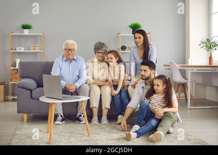 Eine große, freundliche Familie traf sich zu Hause im Wohnzimmer, um einen Film auf einem Laptop anzusehen. Stockfoto