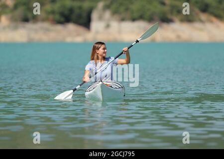 Glückliche Frau, die in einem Kajak rudert und Side in einem wunderschönen See betrachtet Stockfoto