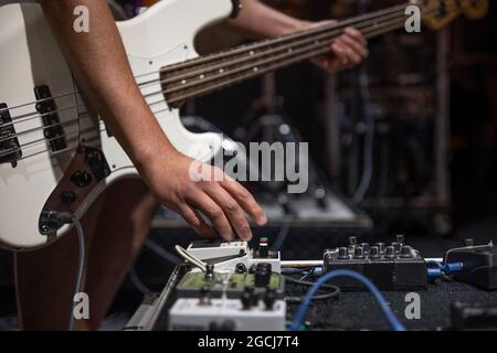 Ein männlicher Gitarrist, der auf der Bühne Audio-Verarbeitungseffekte für die Gitarre einspielt. Stockfoto