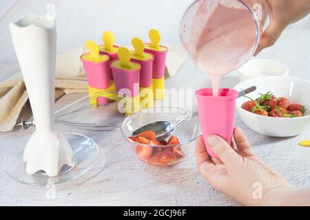 Hausgemachte Eiscreme mit Beeren zubereiten. Die Hände der Frauen halten eine Eisform. Stockfoto