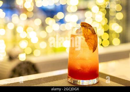 Ein Glas Sekt aus der Nähe, ein Cocktail mit Grapefruit am Fenster und goldenem Bokeh-Hintergrund. Stockfoto
