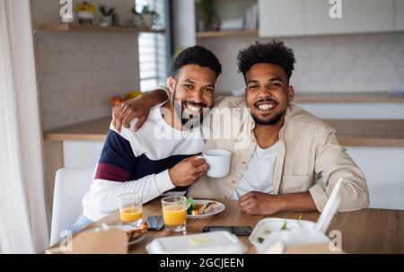 Porträt von jungen erwachsenen Brüdern mit Pizza in der Küche drinnen zu Hause, Blick auf die Kamera. Stockfoto