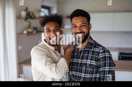 Junge Erwachsene Brüder in der Küche drinnen zu Hause, Blick auf die Kamera. Stockfoto