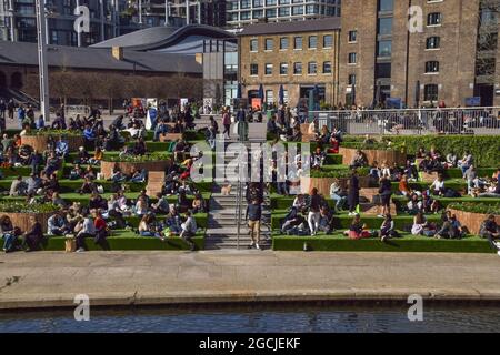 Menschen, die auf den Stufen am Granary Square in King's Cross sitzen. London, Großbritannien, 2021. Stockfoto