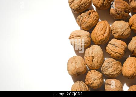 Nahaufnahme von ungeschälten Walnüssen auf hellem Hintergrund. Stockfoto