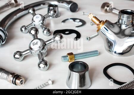 Sanitär - Schrauben, Dichtungen, Teile eines zerlegten Wasserhahns auf weißem Hintergrund Stockfoto