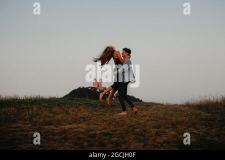 Junges Paar auf einem Spaziergang in der Natur in der Abenddämmerung in der Landschaft, Spaß beim Umarmen. Stockfoto