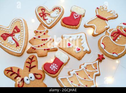Draufsicht auf hausgemachte Weihnachts-Lebkuchenkekse mit rot-weiß gefärbter königlicher Vereisung und verschiedenen Formen auf weißem Hintergrund dekoriert. Stockfoto