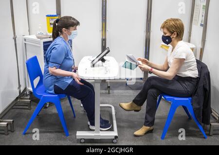 File Photo vom 15/04/21 von Nicola Sturgeon, dem ersten Minister von Schottland (rechts), bevor er die erste Aufnahme des Impfstoffs Astra Zeneca erhielt, der von der Krankenschwester Elaine Anderson im Impfzentrum des NHS Louisa Jordan im SSE Hydro in Glasgow verabreicht wurde. Die Krankenschwester, die Nicola Sturgeon geimpft hat, sagte, dass ihre Erfahrung während der Coronavirus-Pandemie eine „Ehre“ gewesen sei. Ausgabedatum: Montag, 9. August 2021. Stockfoto