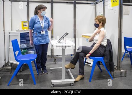 File Photo vom 15/04/21 von Nicola Sturgeon, dem ersten Minister von Schottland (rechts), bevor er die erste Aufnahme des Impfstoffs Astra Zeneca erhielt, der von der Krankenschwester Elaine Anderson im Impfzentrum des NHS Louisa Jordan im SSE Hydro in Glasgow verabreicht wurde. Die Krankenschwester, die Nicola Sturgeon geimpft hat, sagte, dass ihre Erfahrung während der Coronavirus-Pandemie eine „Ehre“ gewesen sei. Ausgabedatum: Montag, 9. August 2021. Stockfoto