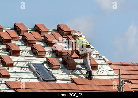 Gestapelte Fliesen und Dachdecker Keepmoat Wohnhäuser Bauherren. Ein Entwicklungsstandort in Chorley. Bauarbeiter beginnen mit dem Bau dieses großen neuen Gehäuses, Dächer Holzlatten Dormer, Ridge Bretter, Sparren und Dormer Bau, Dachträger, Wangenfaszienbrett Holzbretter Soffit Rahmen und Verkleidung Spitze Dachhölzer. Dachschürze auf grünem Gelände, Großbritannien Stockfoto