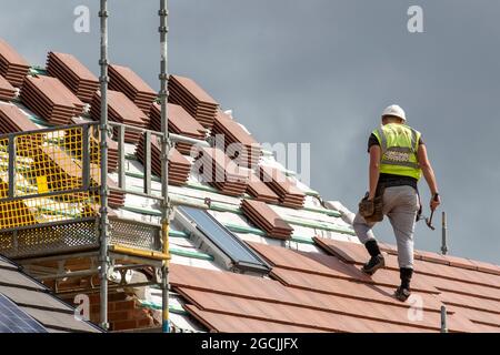 Roof Slater Tiler Keepmoat heims property developers, a Development site in Chorley. Bauherren beginnen den Bau auf diesem großen neuen Gehäuse, Dächer Holzlatten Dachgaube, Ridge Board, Dachsparren und Dachgaube Konstruktion, Dachträger, Wangen Faszien Board Holzboarding soffit Rahmen und Verkleidung Apex Dachhölzer. Dachgaube auf Grünflächen, Großbritannien Stockfoto