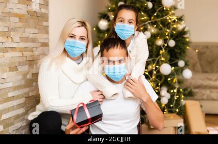 Menschen mit Geschenken tragen Gesichtsmasken während Coronavirus und Grippe Ausbruch an Weihnachten. Schutz vor Viren und Krankheiten, Quarantäne zu Hause. COVID-2019 Stockfoto