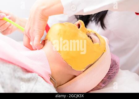 Der Prozess der Entfernung der kosmetischen goldenen Masse, kosmetische Verfahren im Salon. Neu Stockfoto