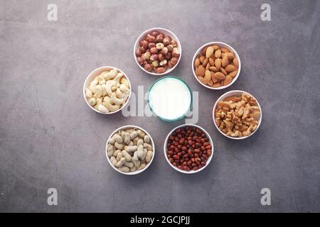 Milch, Erdnuss, Haselnuss, Cashewnuss und Mandel in einem Behälter auf schwarz Stockfoto