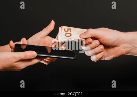 Ein Beispiel für den Einzelhandel mit Smartphones, die Zahlung von Waren in bar, das Empfangen von Geld für verkaufte Waren. Neu Stockfoto