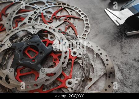 Abgenutzte Mountainbike-Bremsscheiben liegen in der Werkstatt neben dem Scheibenglätterwerkzeug. Stockfoto