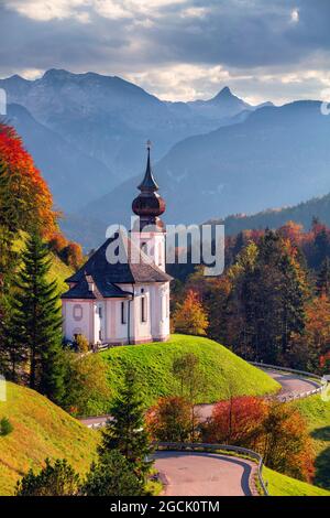 Herbst in den bayerischen Alpen. Landschaftsbild der Bayerischen Alpen mit Maria-Gern-Kirche und Watzmann-Berg bei schönem Herbstuntergang. Stockfoto