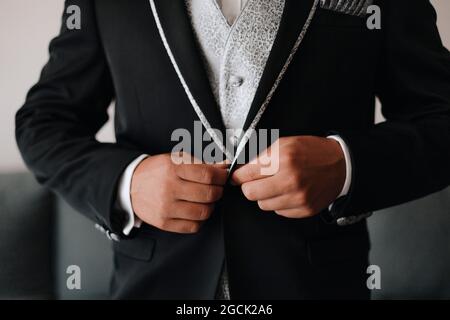 Crop unkenntlich Mann knöpfend stilvolle elegante schwarze Bräutigam Jacke während der Vorbereitung für die Hochzeitszeremonie Stockfoto