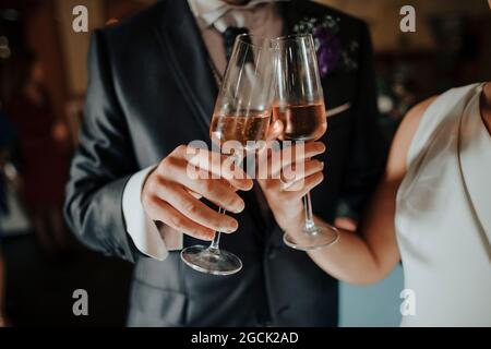 Crop anonyme Braut und Bräutigam in eleganten Hochzeitskleidung klickenden Weingläser mit Champagner während der Feier Stockfoto