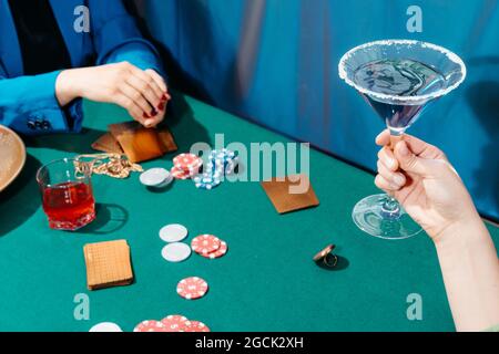 Crop unkenntlich weibliche Freunde sitzen am grünen Tisch mit Karten und Poker-Chips während des Glücksspiels Stockfoto