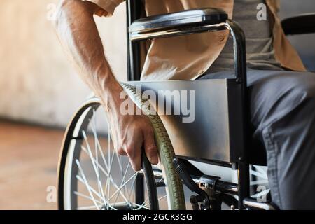Nahaufnahme eines modernen Mannes im Rollstuhl mit Fokus auf dem Rad, Kopierraum Stockfoto