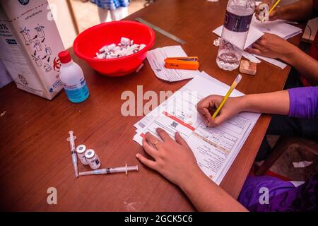 Non Exclusive: BARISHAL, BANGLADESCH - AUGUST 7: Arbeiter registrieren Menschen, bevor sie während eines Massenimpfens die Dosis des Impfstoffs Moderna Covid-19 erhalten Stockfoto