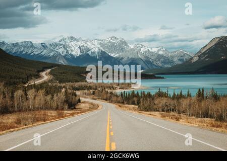 David Thompson Highway in der Nähe des Abraham Lake und schneebedeckter Berge am bewölkten Tag im Banff National Park Stockfoto