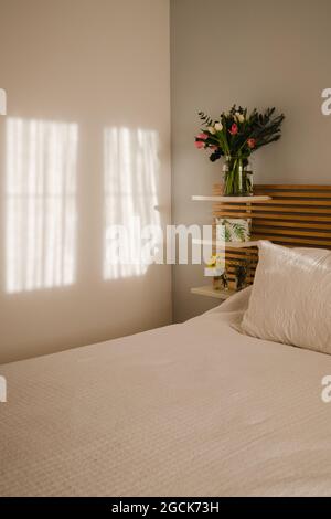 Erstaunlicher Blumenstrauß von Tulpen und Dekoration in der Nähe des Bettes in einem hellen und sonnigen Zimmer Stockfoto