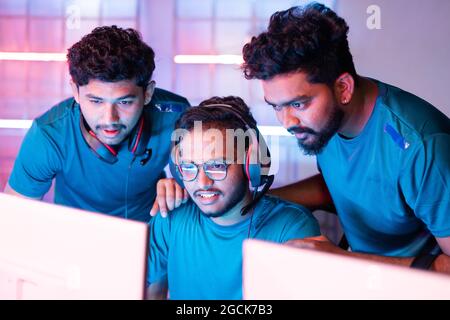 Team von Spielern diskutieren über das Spiel durch Blick in Monitor bei eSports Meisterschaft Liga - Konzept der Teamarbeit, Strategie, Zweisamkeit und in Stockfoto