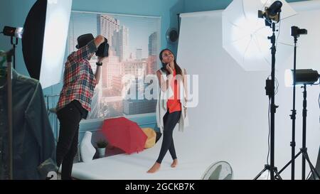 Hinter den Kulissen bei Fotoshooting: Fotograf fotografiert im Studio mit professioneller Ausstattung schönes schwarzes Modell. Stockfoto