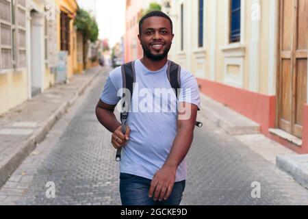 Schwarzer Mann, der Rucksack trägt, während er in der Stadt spazieren geht Stockfoto