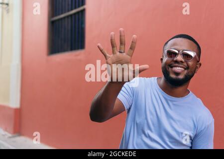Lächelnder afrikanischer Mann, der seine Hand zeigt, während er im Freien geht Stockfoto